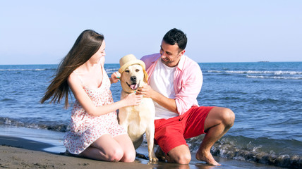Happy family playing with dog on beach