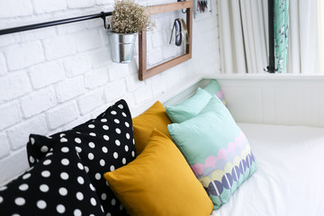 Colorful pillows on a sofa with white brick wall in background