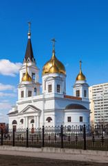 Fototapeta na wymiar White cathedral with golden domes of the forged fence on a sunny