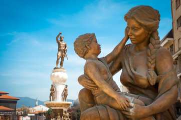 Statue of mother & son and statue of Alexander the Great in back - obrazy, fototapety, plakaty