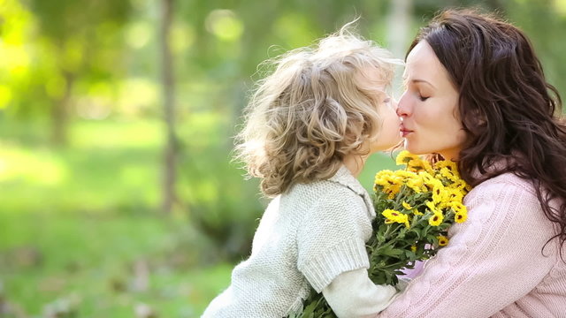 Mother and child with bouquet of flowers in autumn park