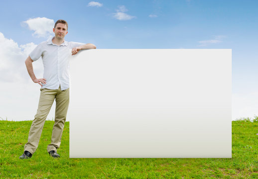 Man Standing In A Field With A Large Blank Sign