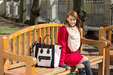 redhaired woman crossing sitting on the bench in park