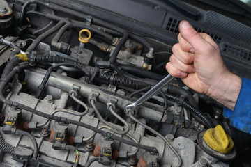 Auto Mechanic is working on engine in car repair shop.