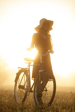 Girl on a bike in the countryside in sunrise time