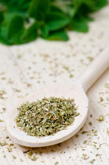 Dried oregano leaves on wooden spoon