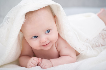 baby looking at camera under a white blanket