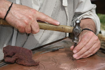 old craftsman Mason during the processing of a copper with an en