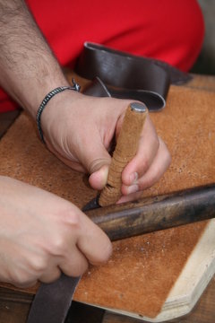 expert craftsman working leather with awl and hammer