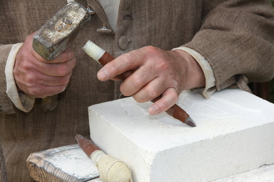 old craftsman Mason during the processing of a piece of white ma