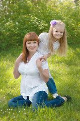 A young girl with her mother on the green grass