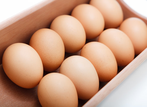 Eggs in wood tray over white background