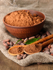 Cocoa powder and cocoa beans on wooden background