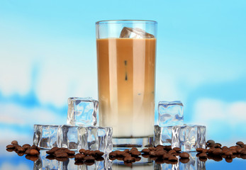 Cold coffee with ice in glass on blue background