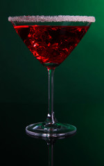 Red cocktail in martini glass on dark green background