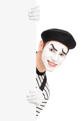 Fototapeta na wymiar A smiling mime artist posing behind a blank panel