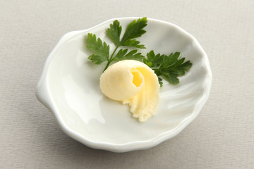 Butter curl on plate on grey background