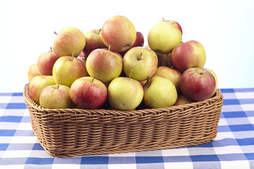 Korb mit Äpfeln auf karierter Tischdecke