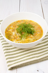 Yellow pea soup in bowl on white wooden background