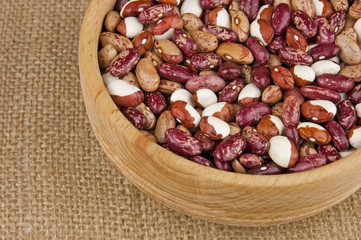 Multicolored pinto kidney beans mix in wooden bowl close up