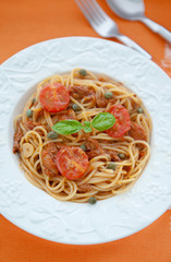 Spaghetti with tuna and tomatoes sauсe on orange background