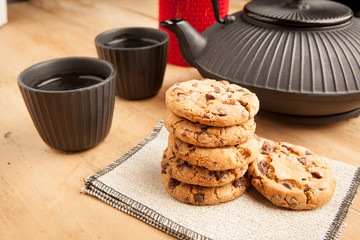 Chocolate biscuits with teapot and mugs, wooden background