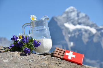 Swiss chocolate and jug of milk against mountain peak. Switzerla