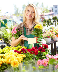 Garden center worker smiling and holding up yellow flower