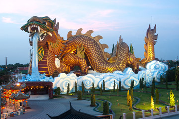 Outdoor night scene of large golden dragon in temple, Thailand.