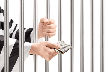 Man in jail holding prison bars and giving bribe