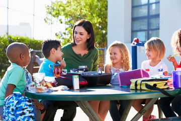 Elementary Pupils And Teacher Eating Lunch