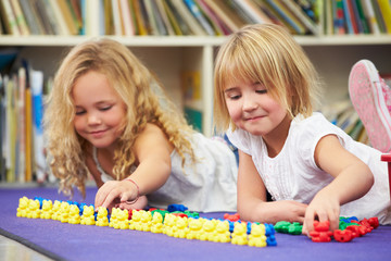 Two Elementary Pupils Counting Together In Classroom