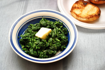 Bowl of Cooked Spinach with a Pad of Butter