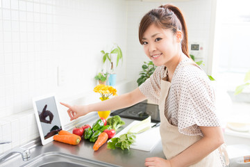 Obraz na płótnie Canvas タブレットを見ながら料理をする女性