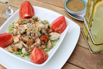 Plato de mariscos con ensalada sobre una mesa de madera
