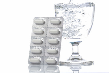 A pack of pills with a glass of water