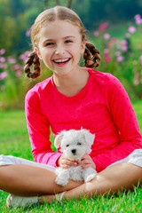 Lovely girl with cute puppy in the garden