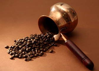 Coffee pot with coffee beans on brown background
