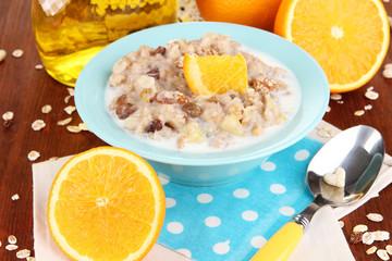 Useful oatmeal in bowl with fruit on wooden table close-up
