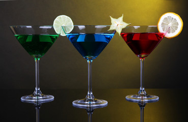 Alcoholic cocktails in martini glasses on dark yellow