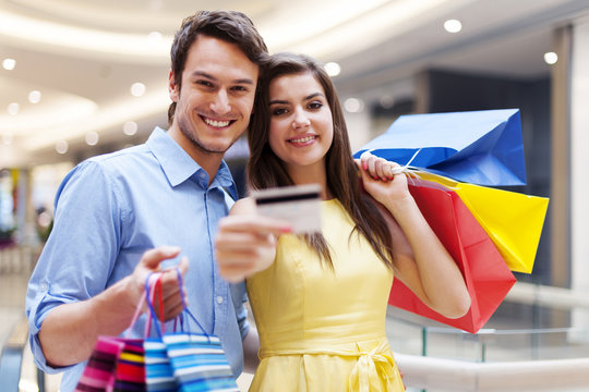 Beautiful couple showing credit card in the shopping mall