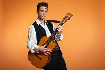 Naklejka premium Retro country male guitar player wearing black suit. Studio shot