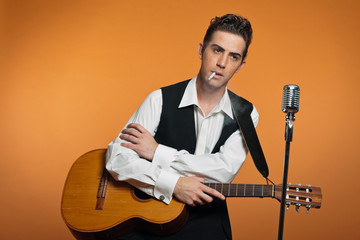 Retro country singer with guitar wearing black suit. Smoking cig
