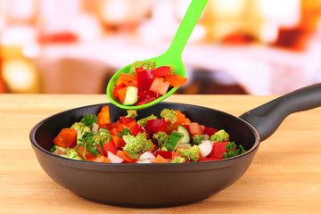 Vegetable ragout in pan,  on wooden table on bright background