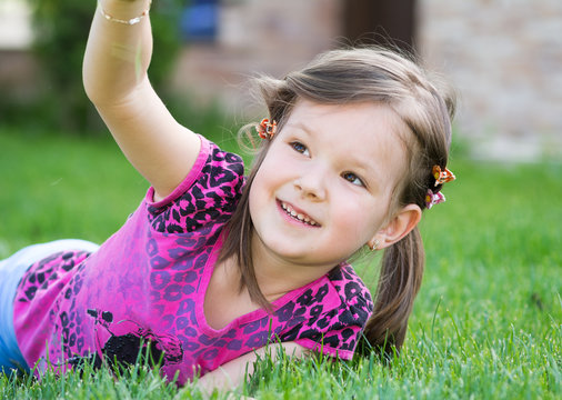 little baby girl playing with grass in the summer garden