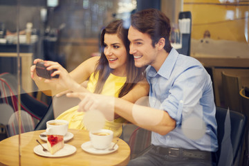 Happy couple taking photo in cafe