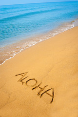 Fototapeta na wymiar Word Aloha written in sandy on tropical beach