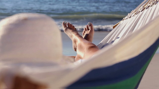 Woman relaxing on the beach in a hammock