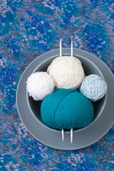 Bright balls of yarn and knitting needles on a plate