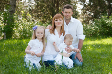Fototapeta premium Happy beautiful family sitting on a green grass